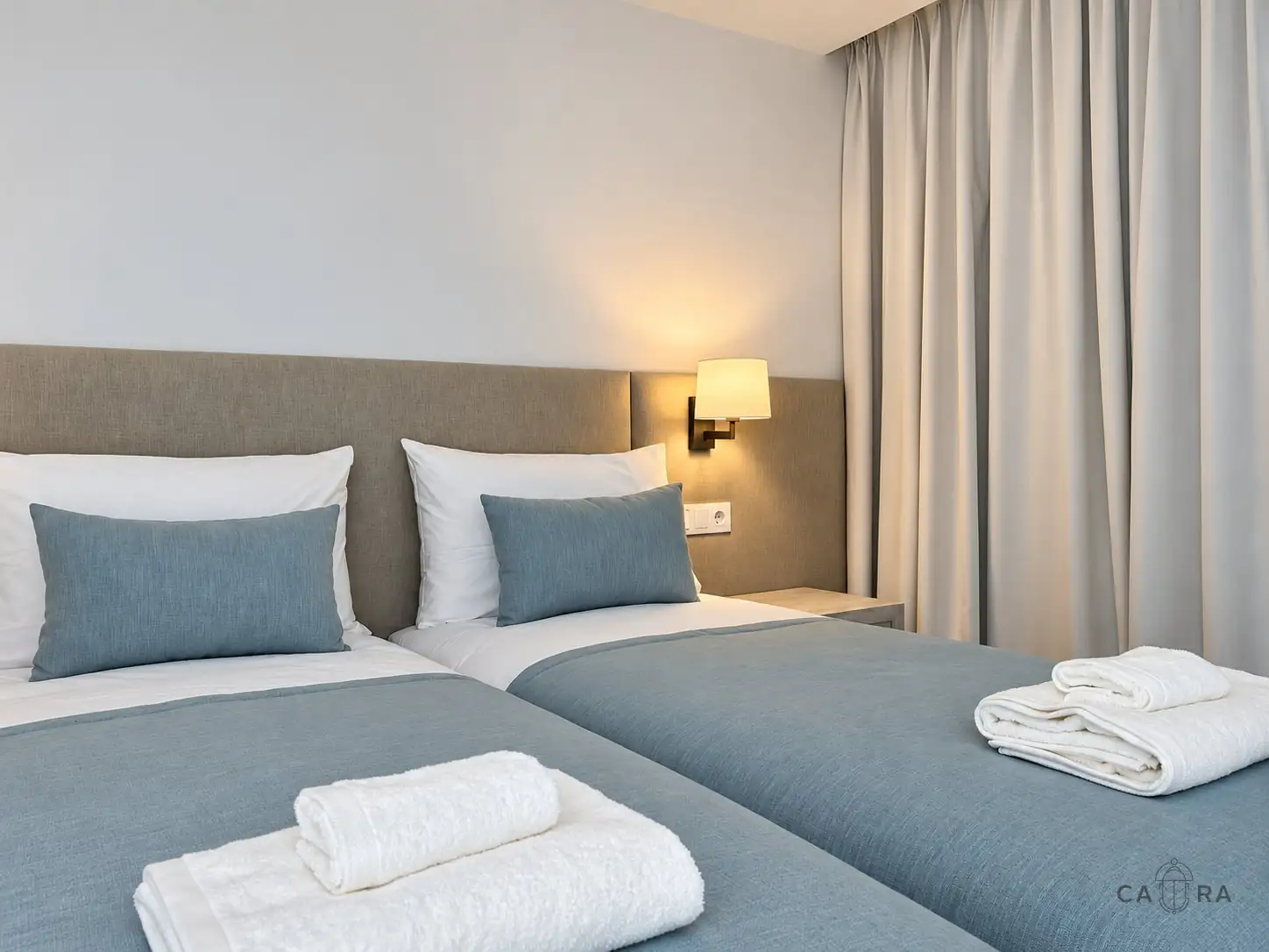 Twin bedroom with blue throws and folded towels