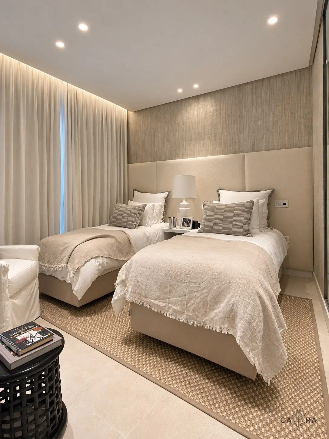 Twin bedroom with a continuous upholstered headboard and sheer curtains
