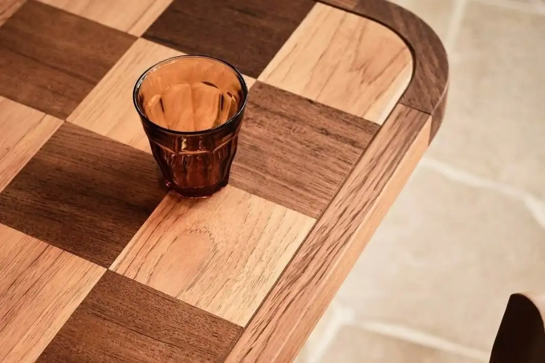 Chequerboard timber table with an amber glass and a terracotta upholstered chair