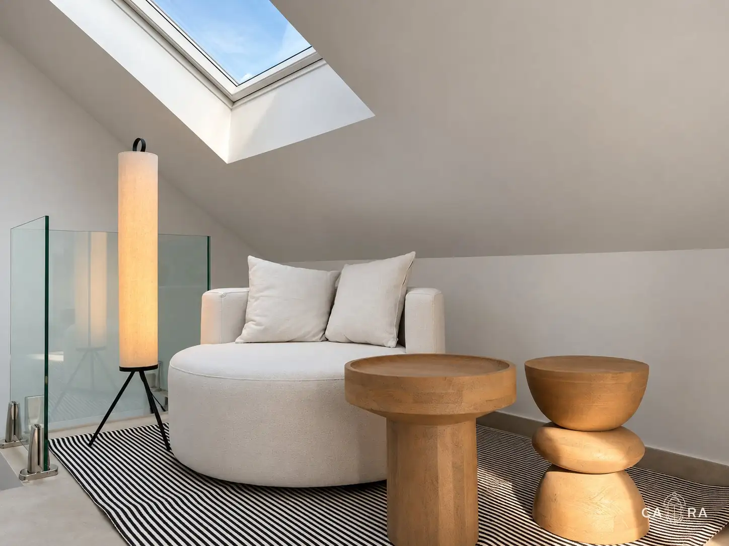 Loft with a round armchair, wooden side tables and skylight