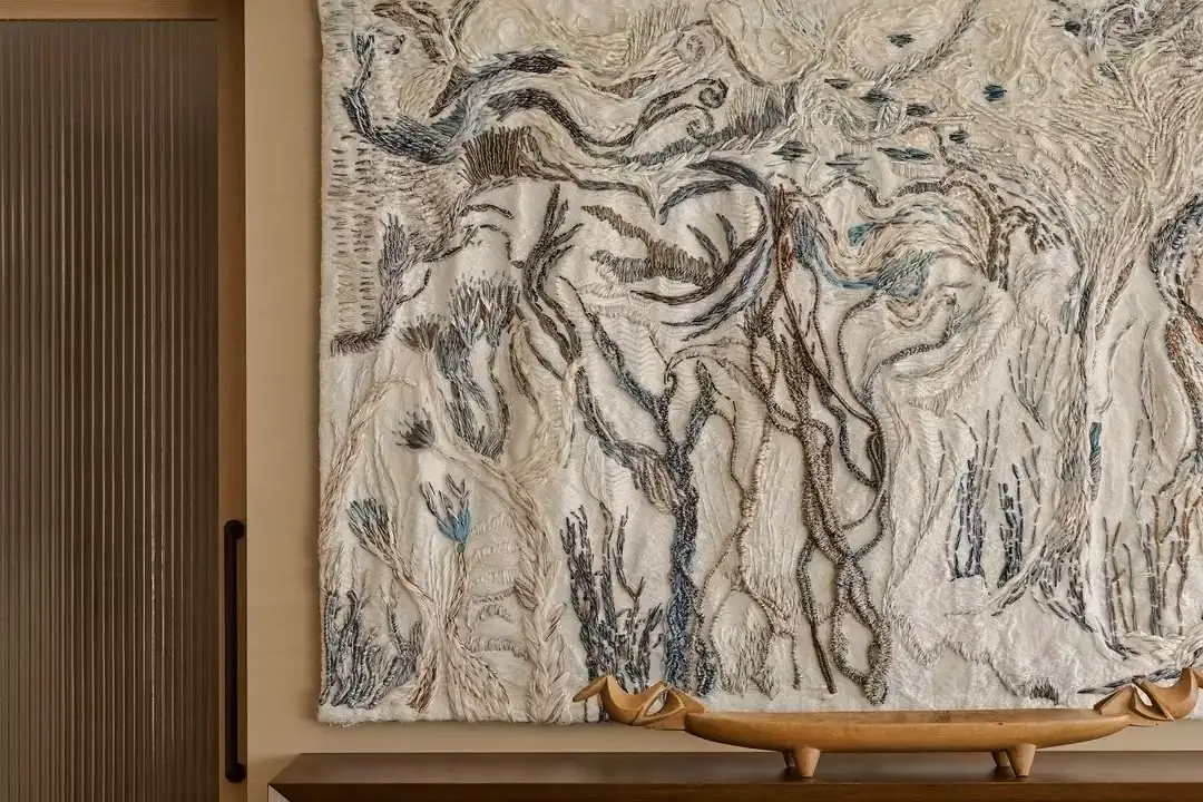 Large textile artwork above a carved timber sideboard
