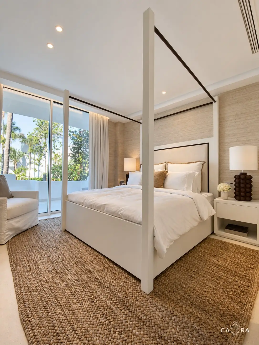 Main bedroom with a white four-poster bed, jute rug and garden views