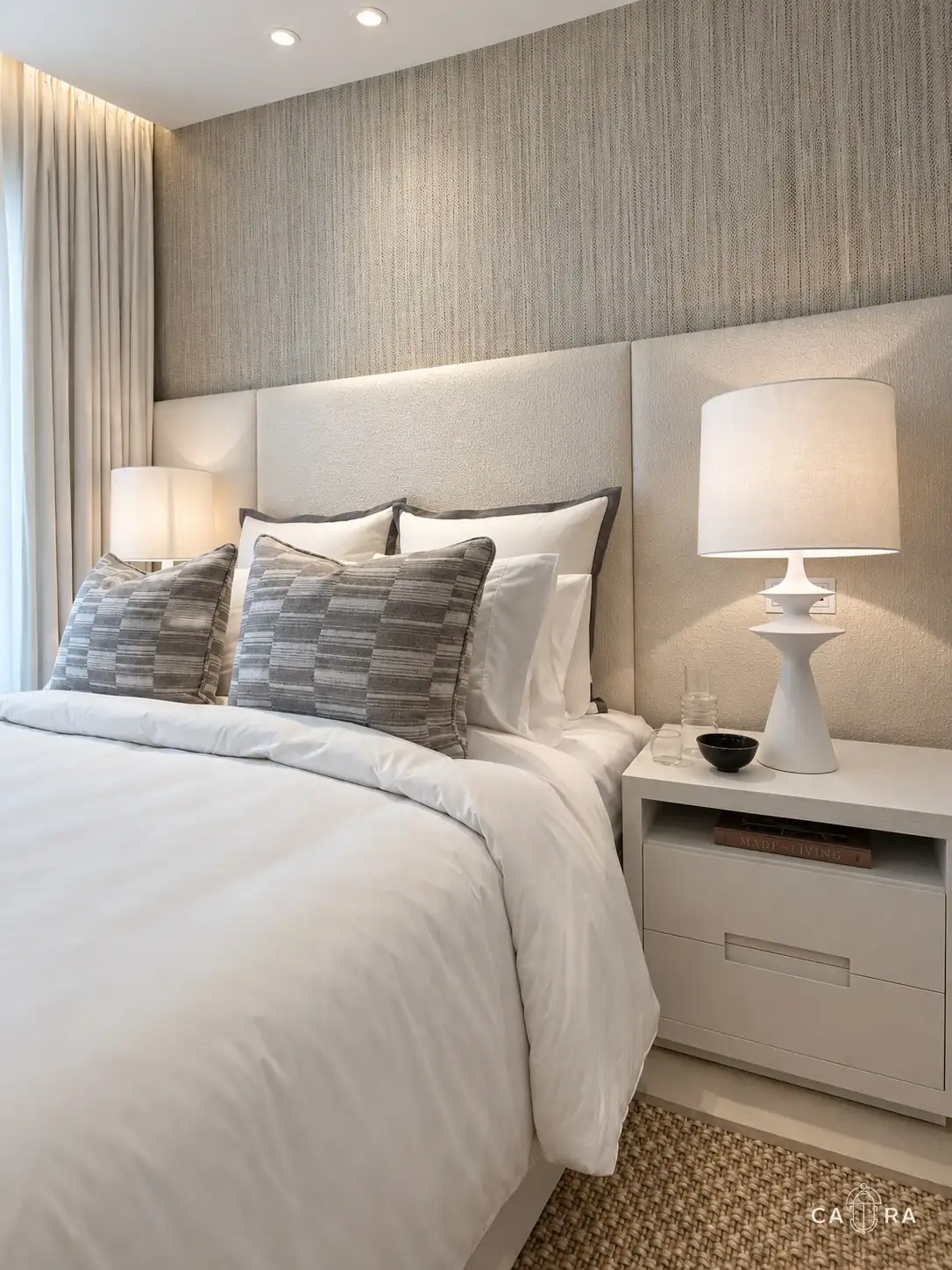 Bedside detail with a sculptural white lamp and textured cushions
