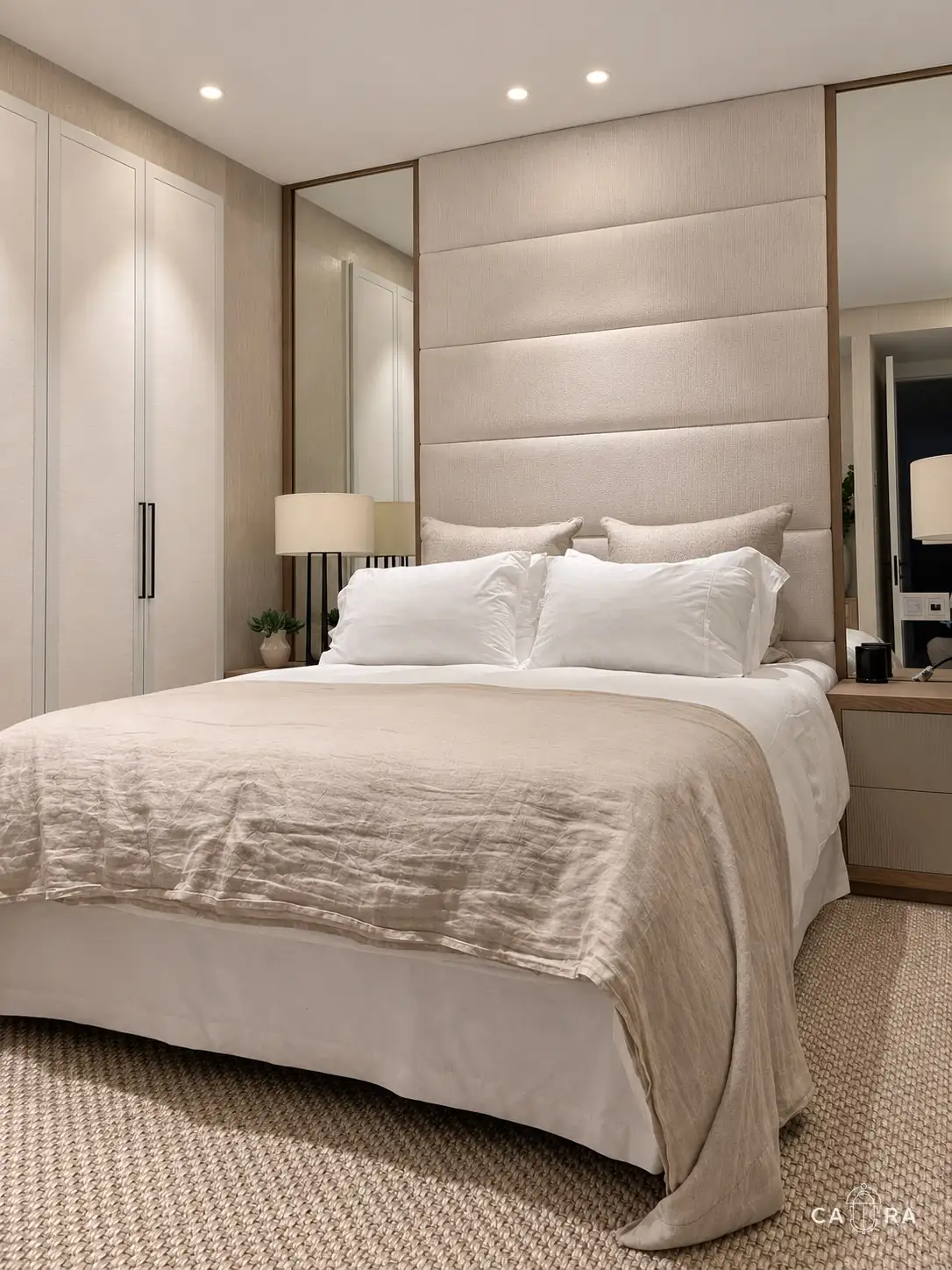 Bedroom with upholstered headboard between oak-framed mirrors and a linen throw