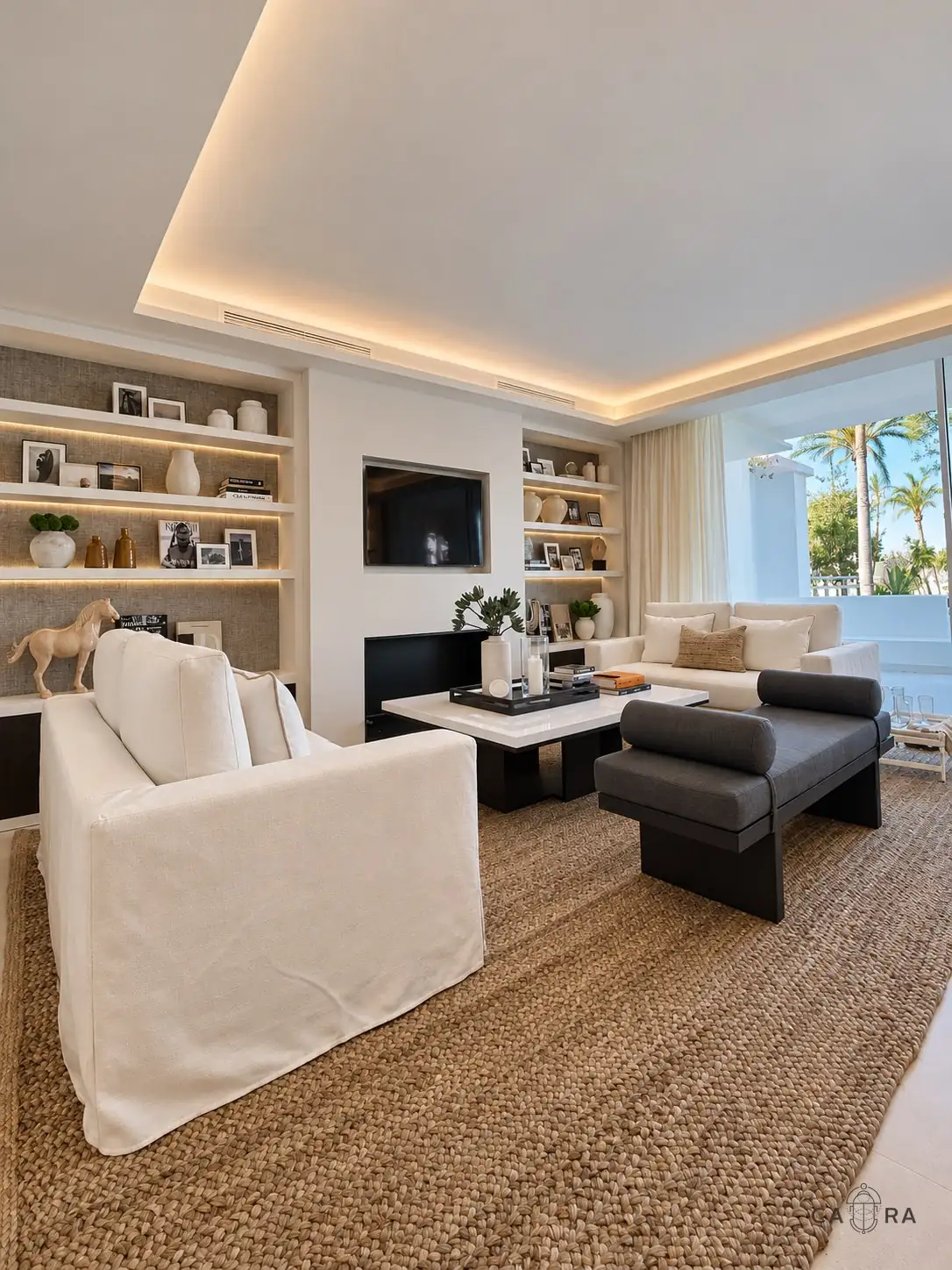 Living room with linen armchair, dark daybed and jute rug opening onto the terrace