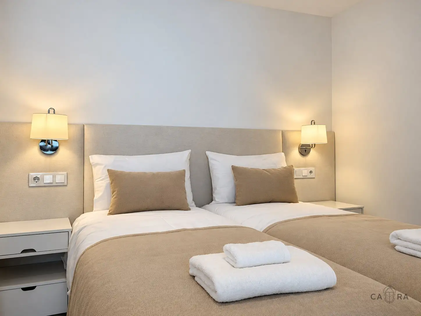 Twin bedroom in sand tones with wall lamps